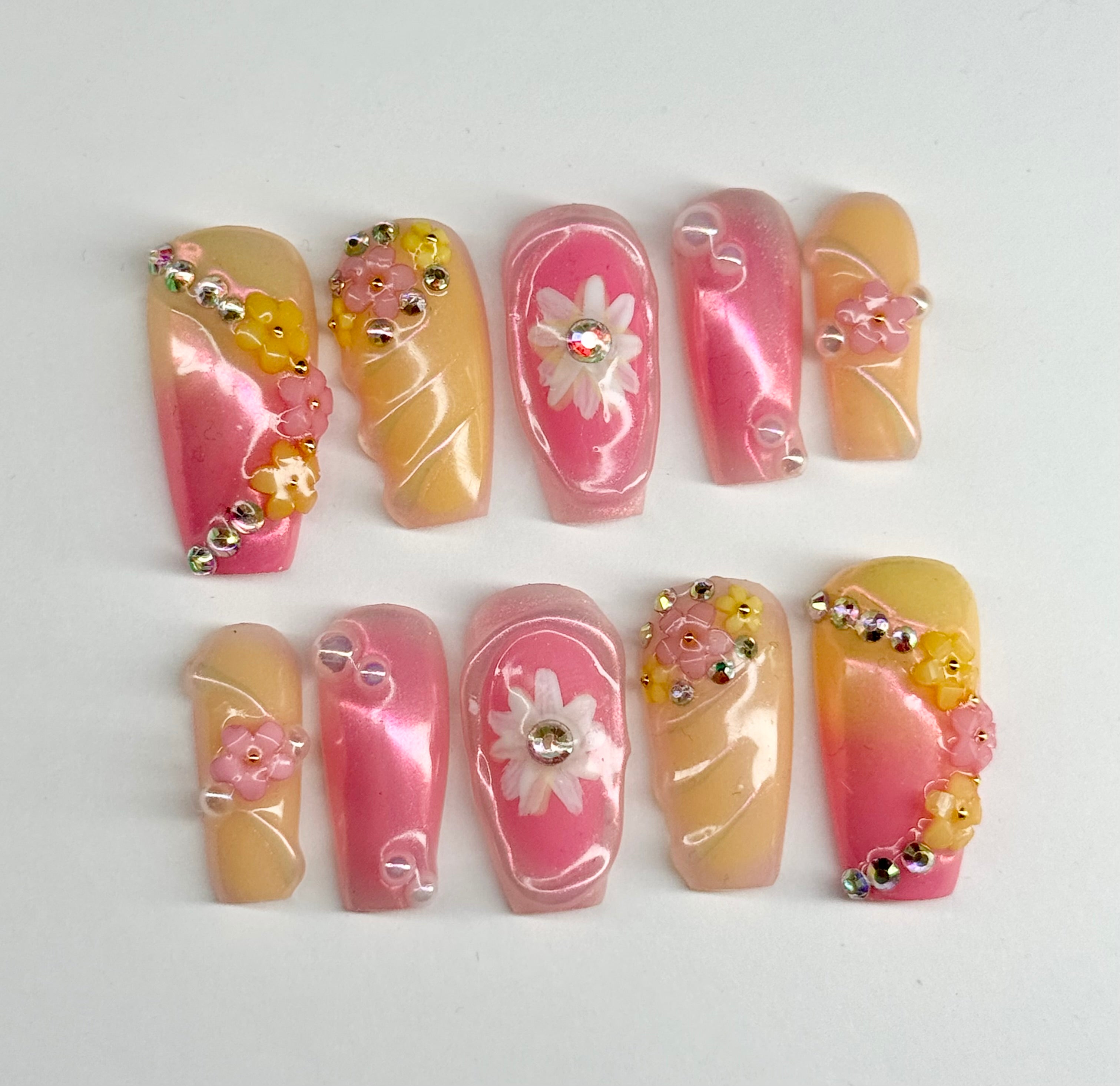 Set of nail art designs with pink, yellow, and white flowers on a white background