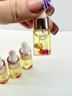 Hand holding a small glass bottle with a dropper filled with yellow liquid on a white background
