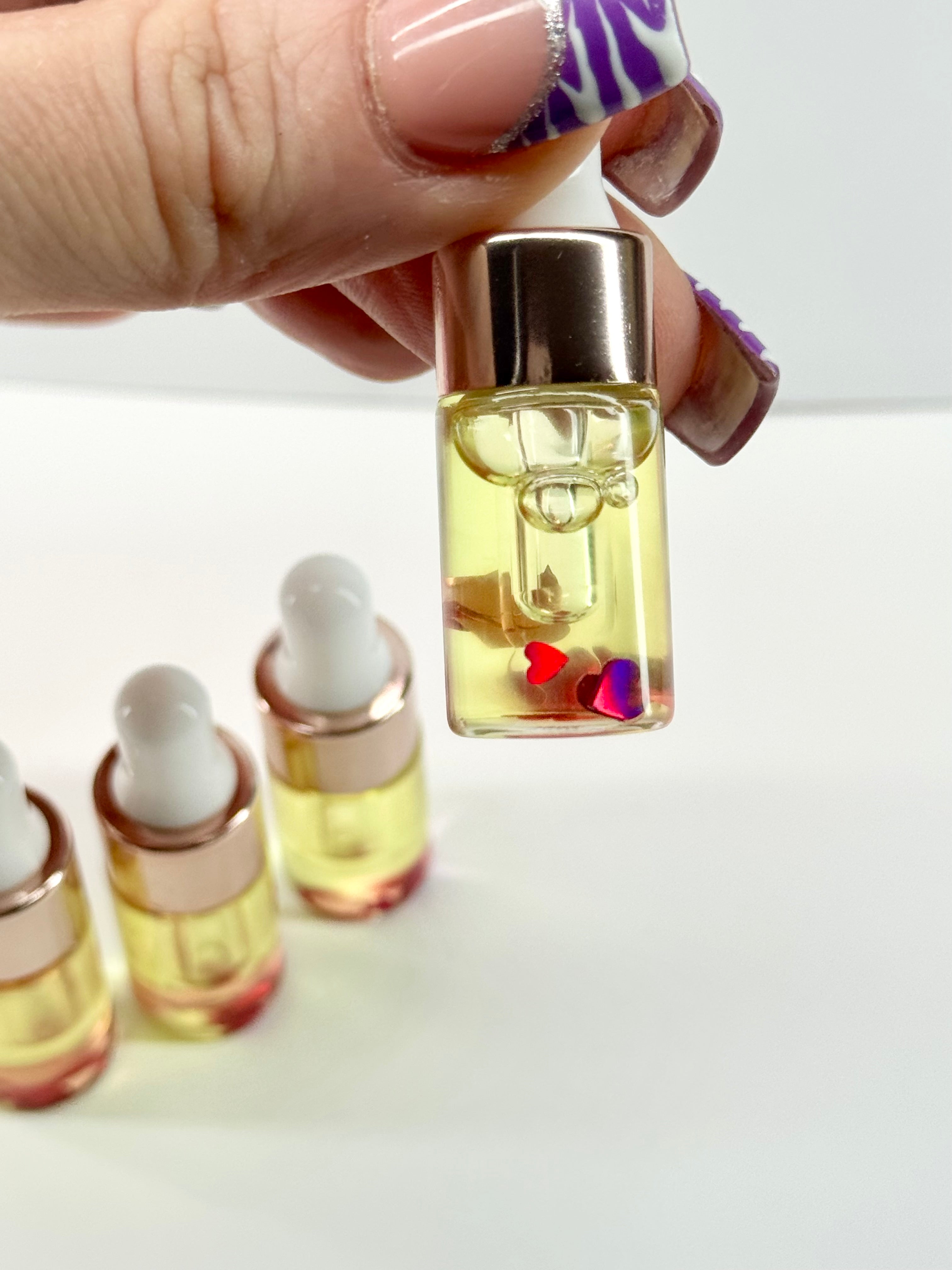 Hand holding a small glass bottle with a dropper filled with yellow liquid on a white background