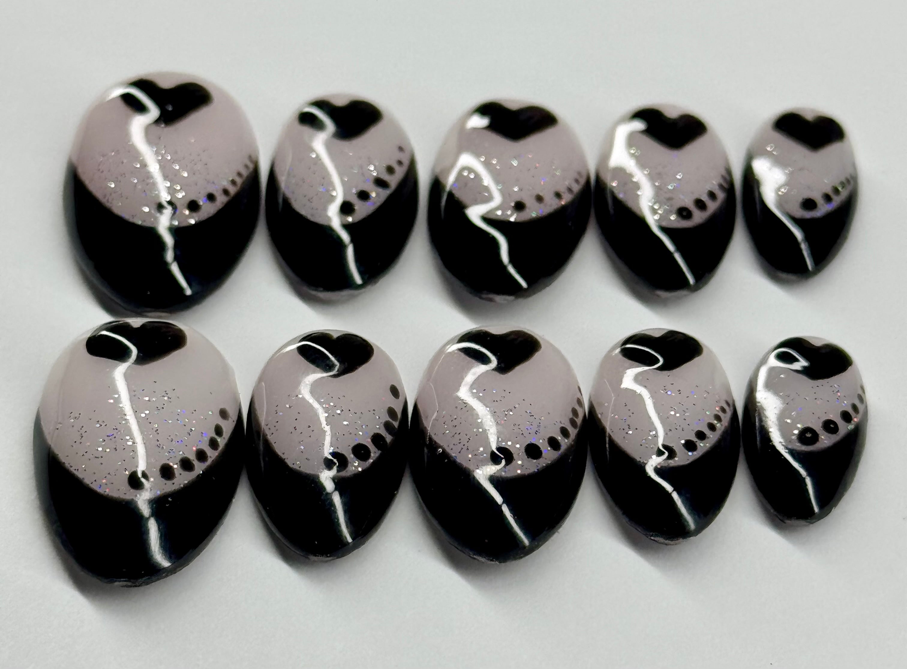 Set of black and white nail art designs on a light gray background