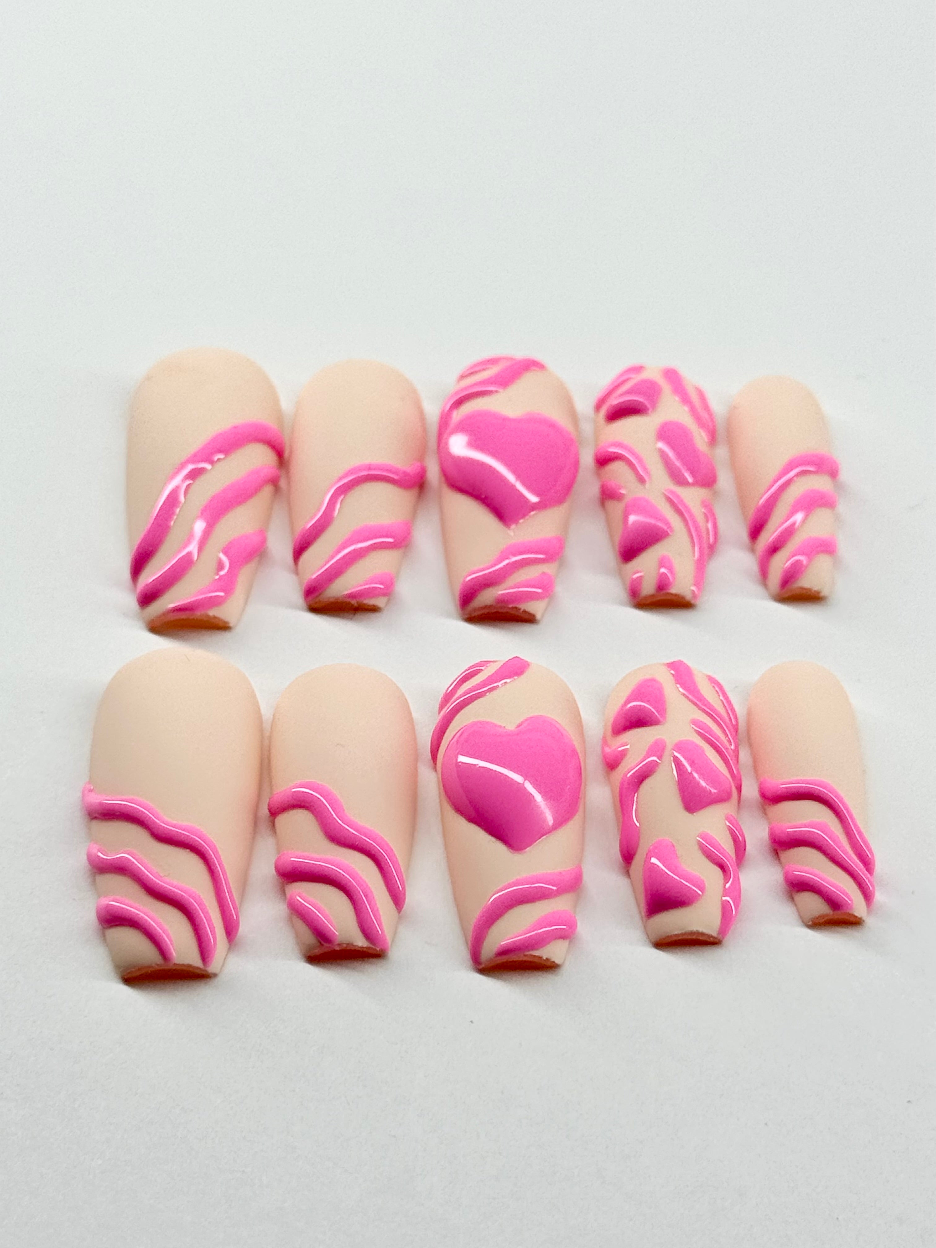 Set of decorative false nails with pink designs on a beige nude background