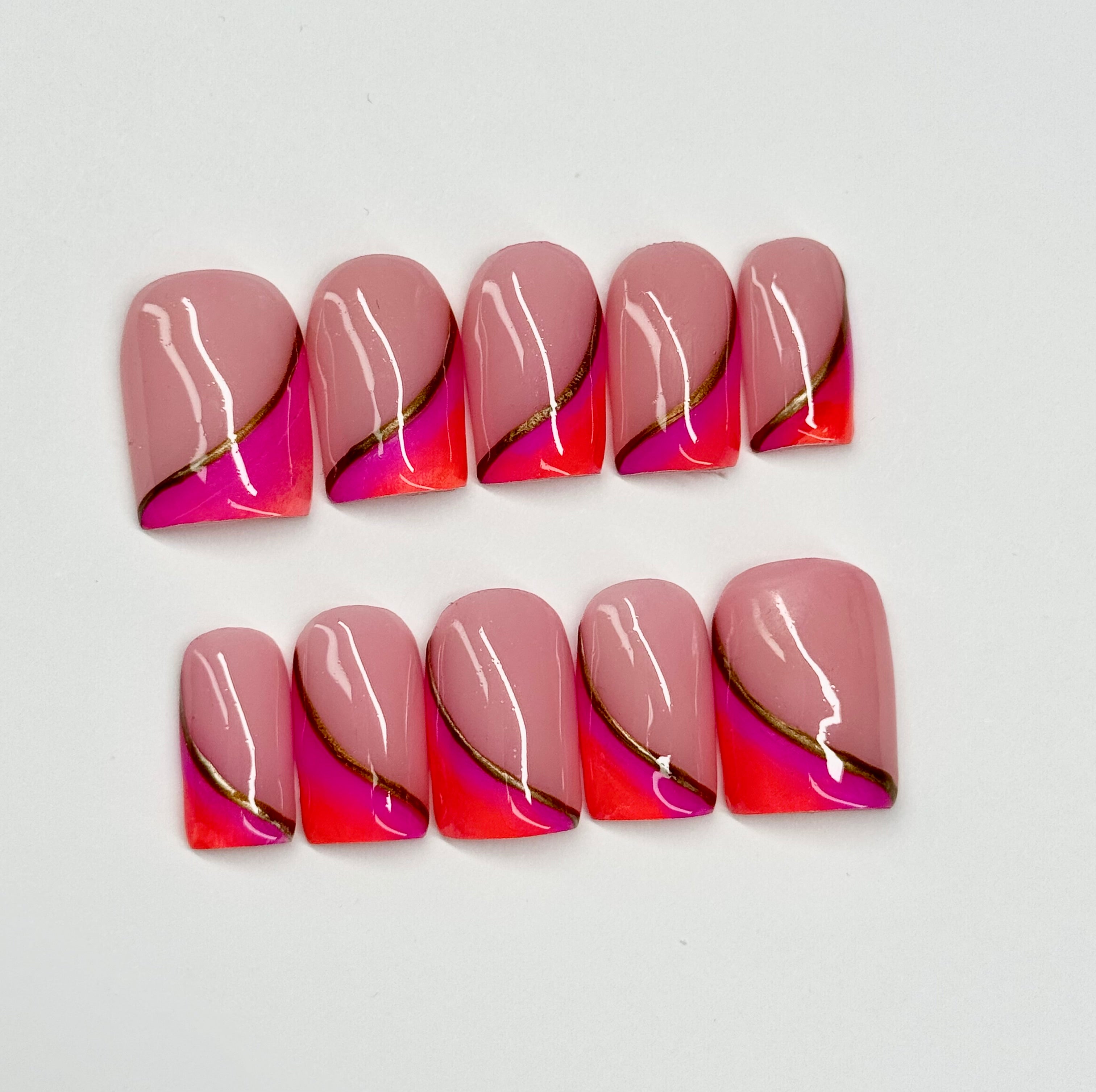 Set of pink and orange nail art with gold accents on a white background