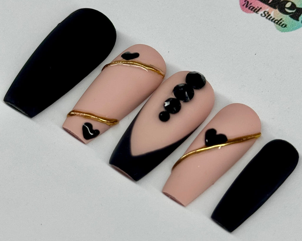 Nail art design with black, gold, and pink on a white background