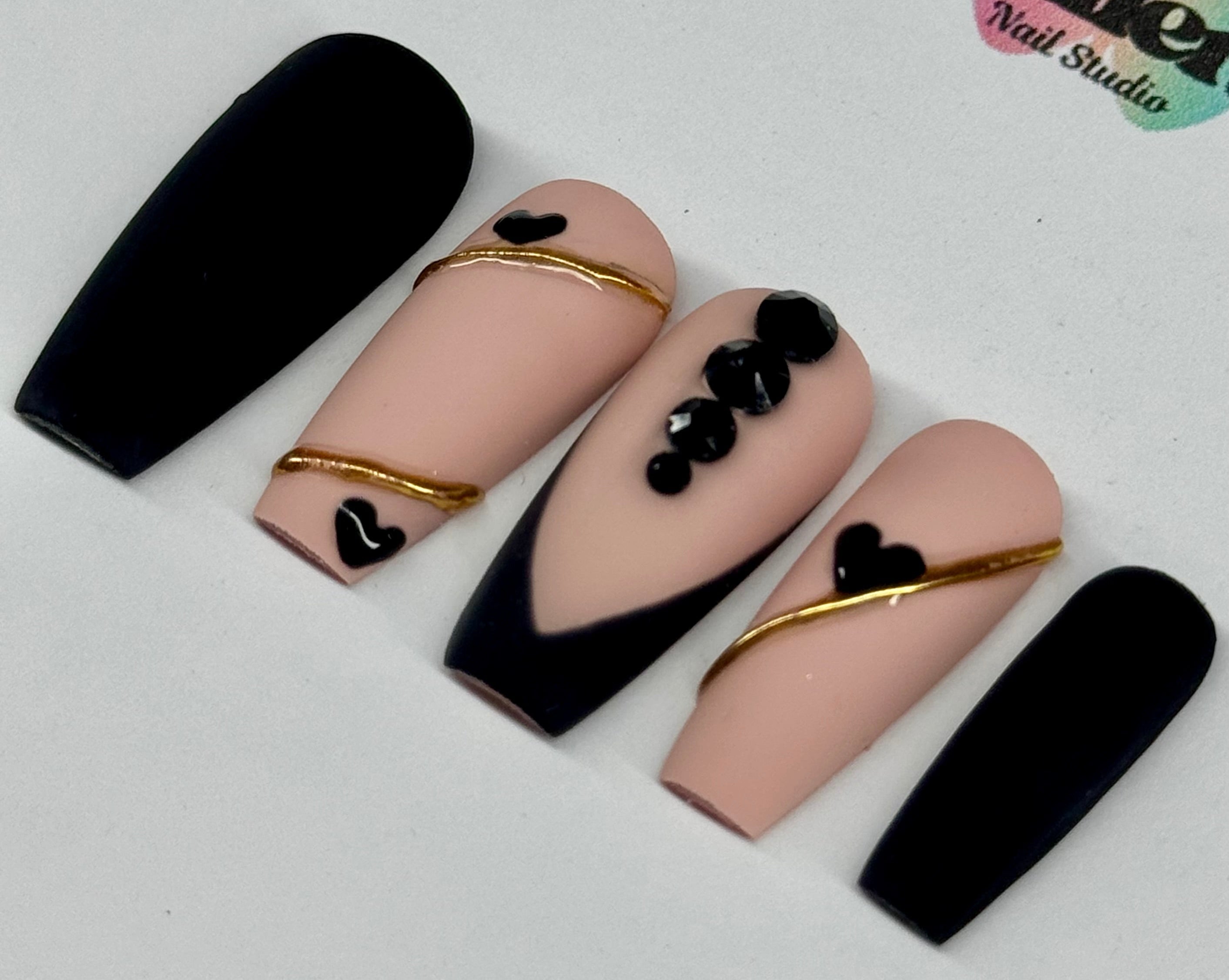 Nail art design with black, gold, and pink on a white background