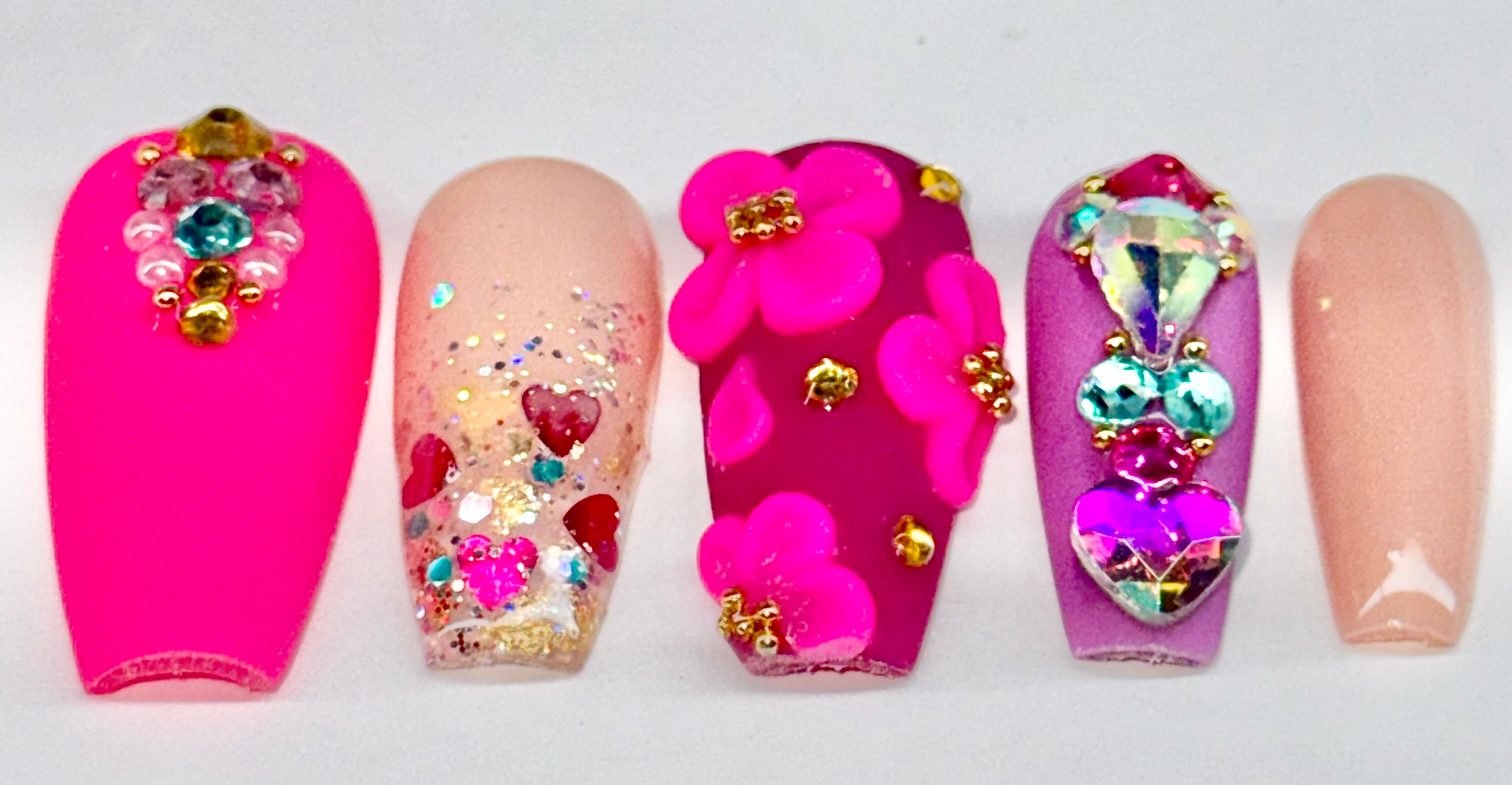Colorful nail art with flowers and heart designs on a white background