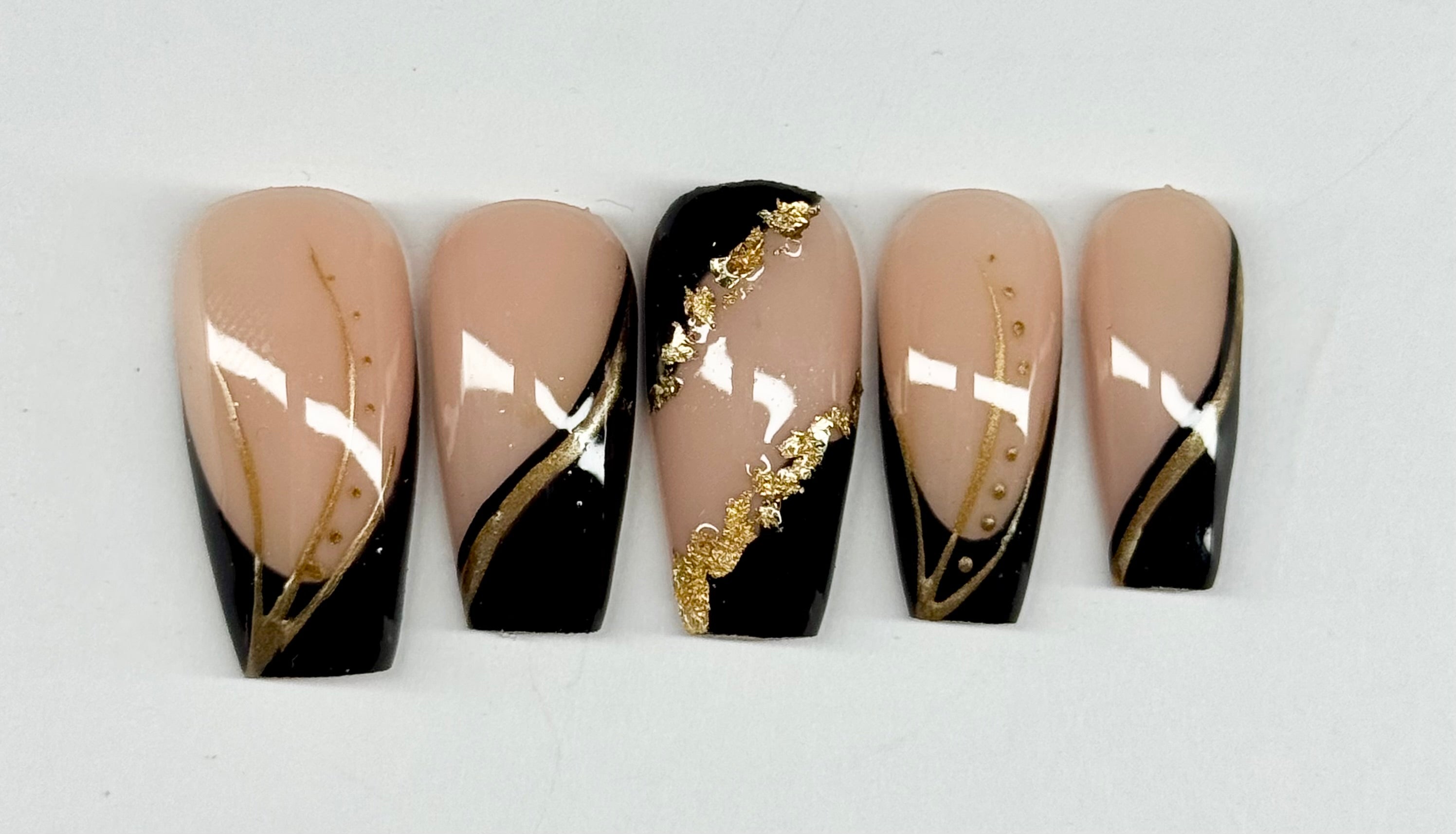 Five nail art designs with black, gold, and beige colors on a white background