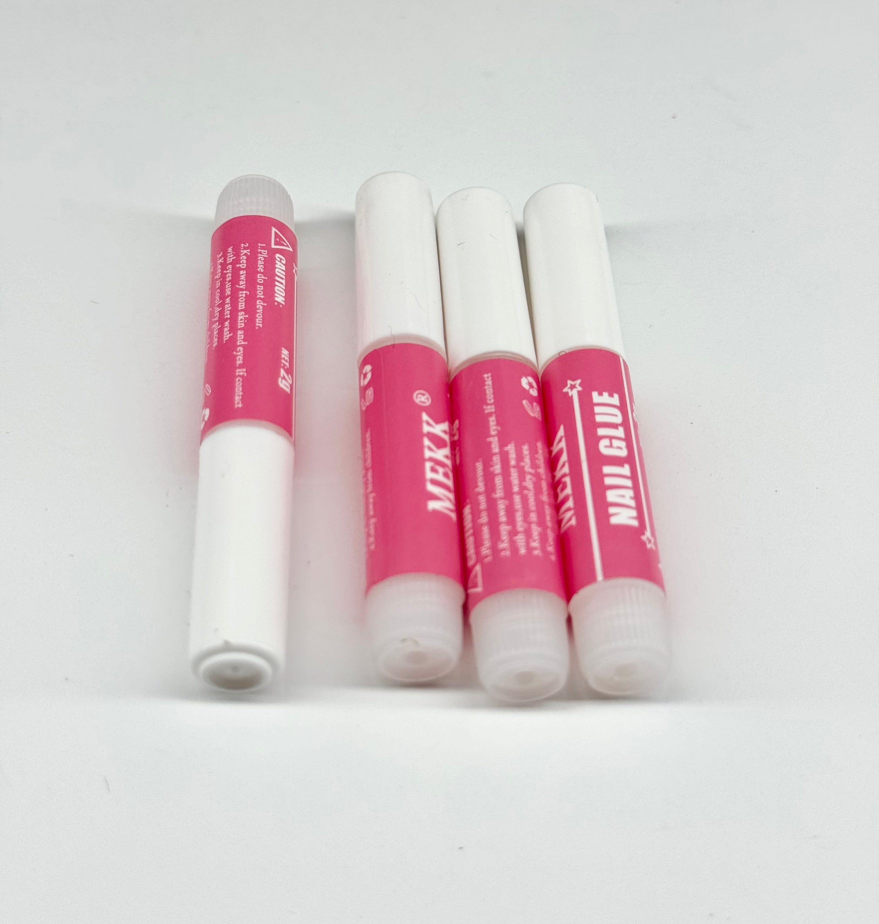 Four tubes of nail glue with pink caps on a white background