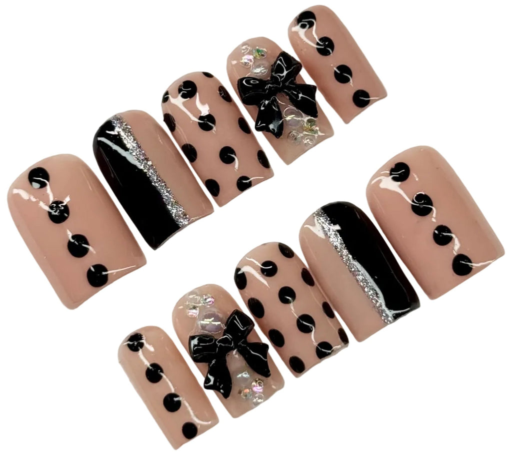 Set of nail art designs with black polka dots and bows on a beige background