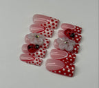 Set of artificial nails with red and white polka dot design on a light gray background