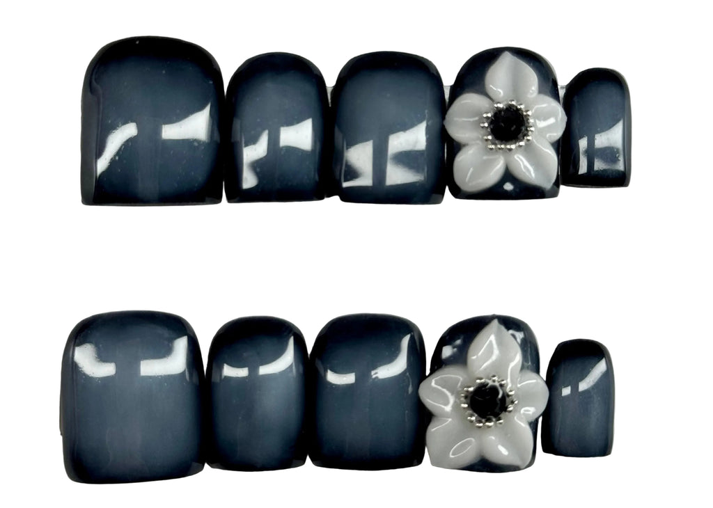 Nail art with black and white flowers on a light gray background