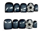 Nail art with black and white flowers on a light gray background