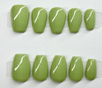Set of green press-on nails with white lines on a white background