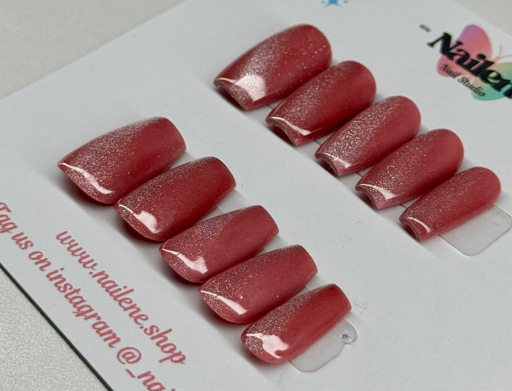 Set of cat eye effect nail extensions on a white card with branding.