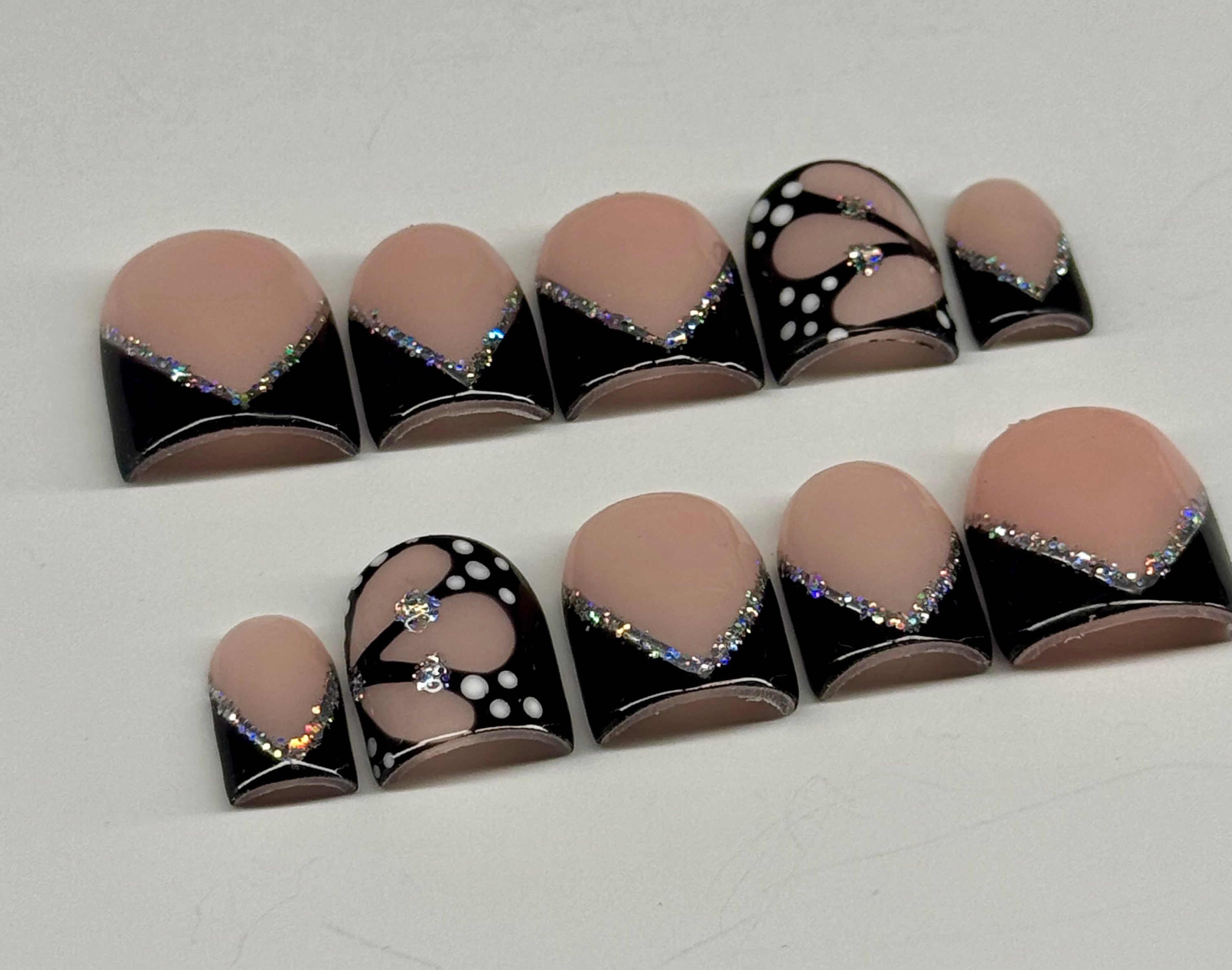 Set of nail art designs with black, white, and beige colors on a white background