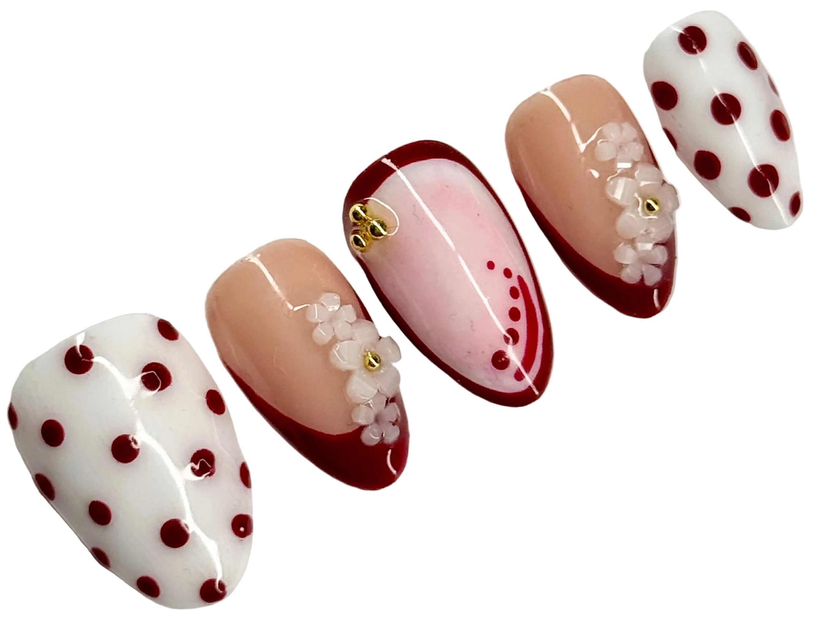 Nail art with polka dots and floral designs on a white background
