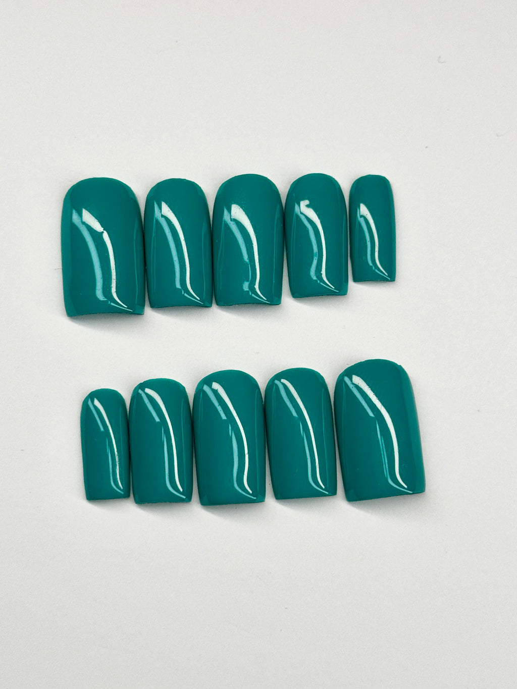 Set of teal nail polish on a light gray background