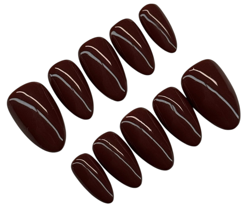 Dark brown nail polish strips on a white background