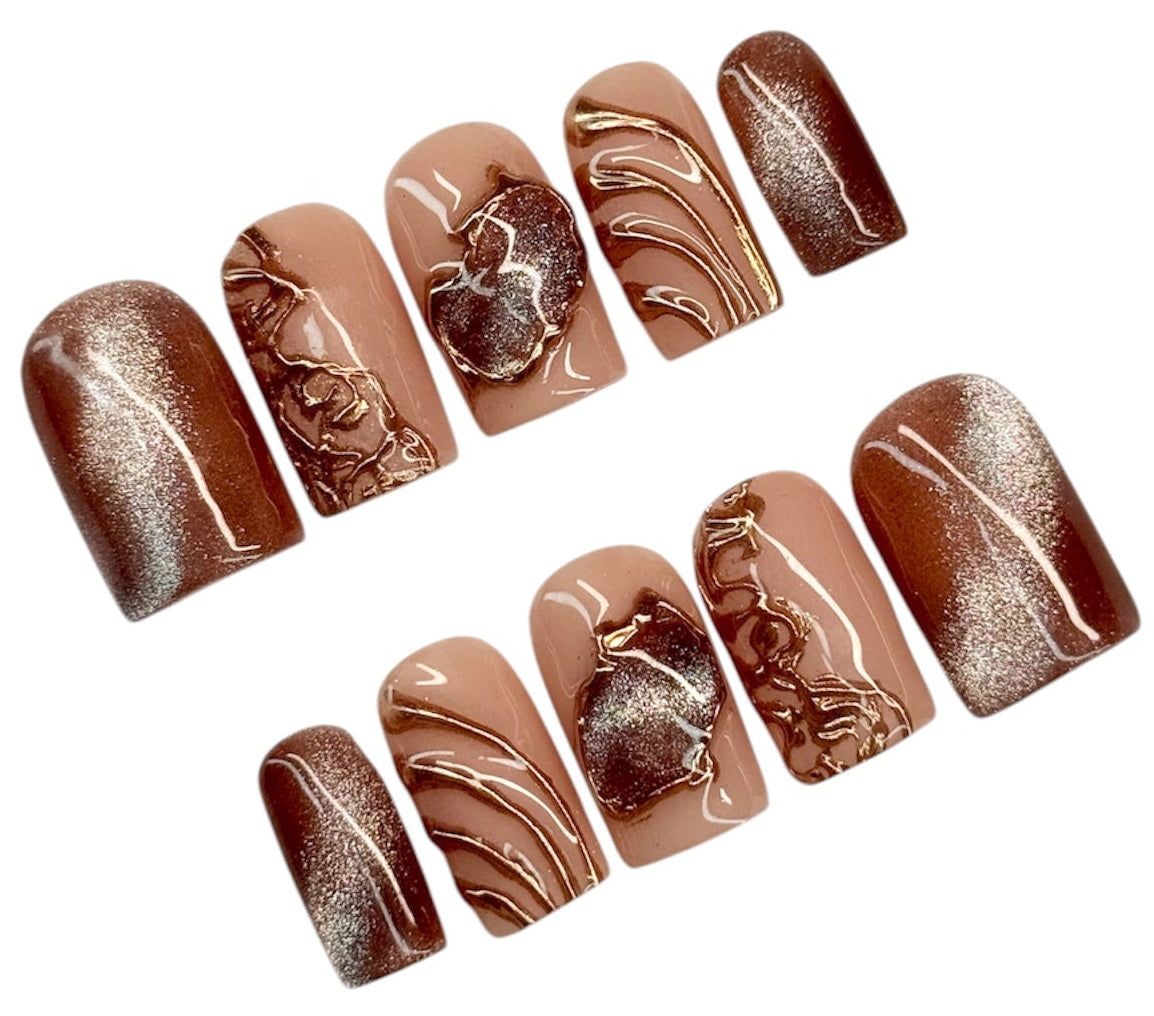 Set of brown cat eye and bronze marbled nail art designs on a white background
