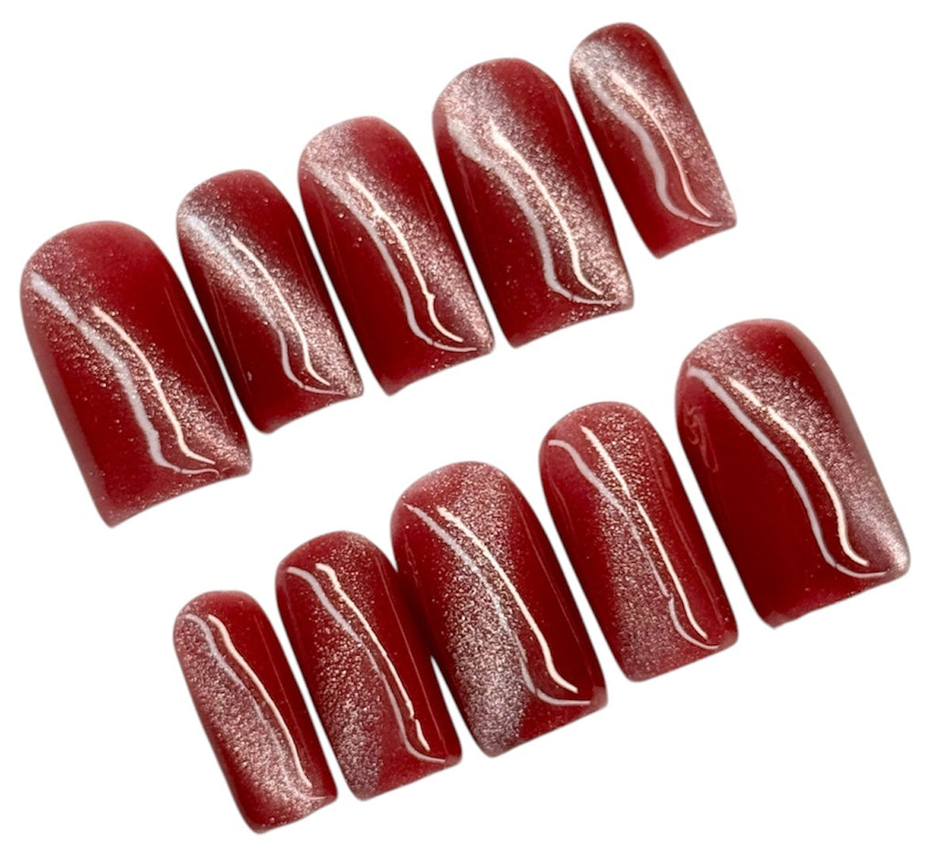Set of dark pink cat eye nail polish strips on a white background