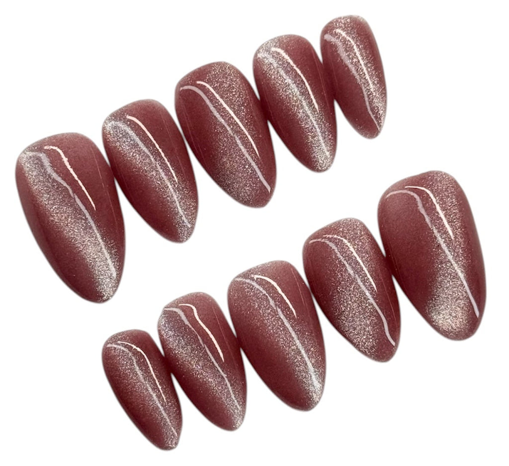 Set of light pink cat eye glittery nail art decorations on a white background