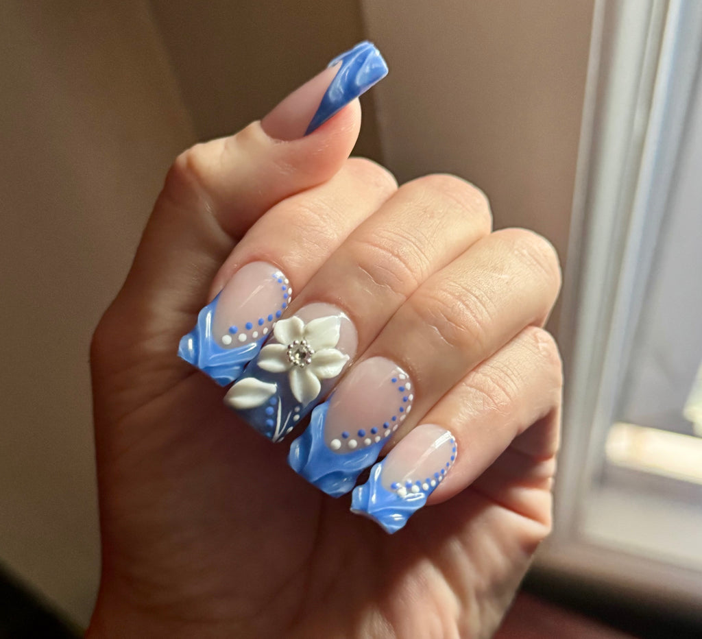 Realistic Hand with blue and white floral nail art on a neutral background