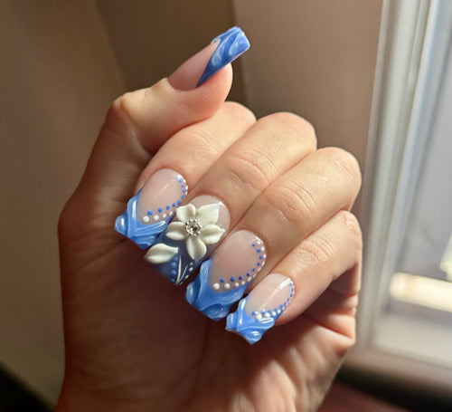 Realistic Hand with blue and white floral nail art on a neutral background