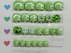 Set of pastel green nail art decorations with various gemstones on a clear plastic strip.